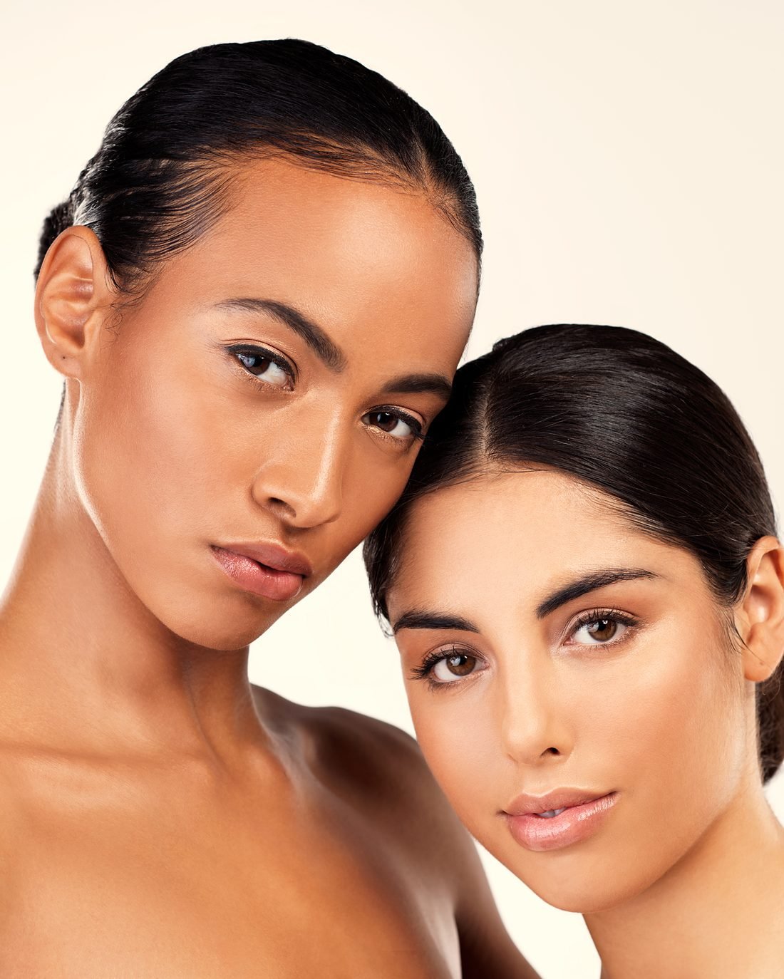 Two women with radiant skin posing cheek to cheek